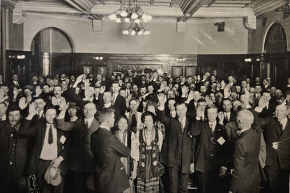 Several dozen new immigrants stand with their right hands raised to take the oath of citizenship. Minneapolis, 1925. Photo from MNHS Collections, locator: J4.8 p5