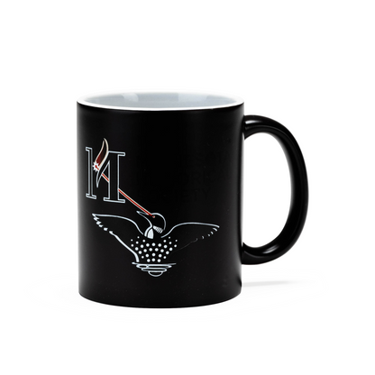 Laser Loon Mug Color Changing featuring a black exterior that reveals a minimalist design with a white letter H, red and white feather, and a stylized Laser Loon adorned with dotted wing patterns. Inspired by the Minnesota Historical Society, this mug showcases the striking imagery against a plain background.