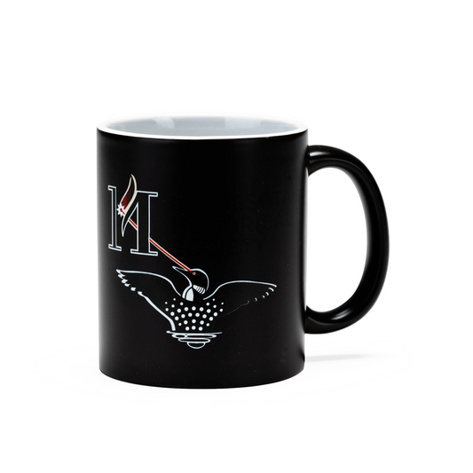 Laser Loon Mug Color Changing featuring a black exterior that reveals a minimalist design with a white letter H, red and white feather, and a stylized Laser Loon adorned with dotted wing patterns. Inspired by the Minnesota Historical Society, this mug showcases the striking imagery against a plain background.