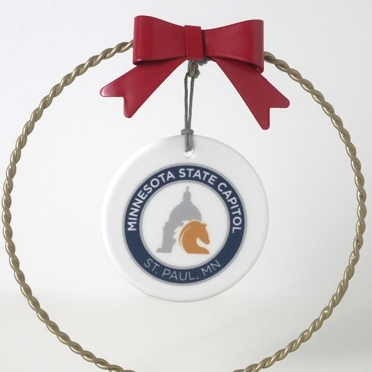 The Site Logo Porcelain Ornament is a circular ceramic piece with a red bow, MINNESOTA STATE CAPITOL ST. PAUL, MN logos encircling the capitol and gold horse head, all framed by a twisted gold ring—perfect as a Minnesota souvenir.