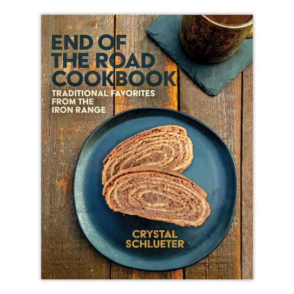 Cover of End of the Road Cookbook: features two slices of rolled bread on a blue plate atop rustic wood with a mug on a slate coaster—a Minnesota cookbook perfect for fans of traditional regional food.