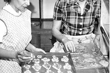 Two women decorate Christmas cookies that are laid out on three baking sheets. Citation: Jacqueline Heinichs and Mrs. Joe LaVasseur making cookies for St. Louis Home and School Association bake sale to raise money for Christmas for the school children.
Location #: GT4.8 p39. MNHS Collections.
